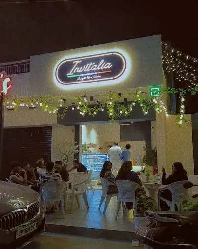 The front of Invitalia in the evening, tables and chairs out on the street under string lights